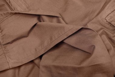 Buruşuk pantolonun en üst görüntüsü. Kahverengi kumaş dokusu arka planı. Pamuk kumaş..