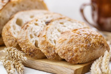 Tahta masadaki keten havlunun üzerinde taze pişmiş buğday ekmeğinin dilimlerini kapatın..