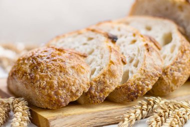 Tahta tahtada buğday kulaklı taze ekmek dilimleri, seçici bir odak noktası..