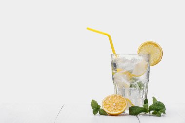 Bir bardak limonlu su, beyaz ahşap masa üzerindeki nane yaprakları ve buz küpleri ışık arka planına karşı, kopyalama alanı. Ferahlatıcı limonata, limonata.
