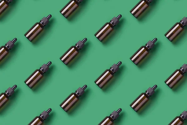 Repetitive pattern with glass bottles for cosmetics, essential oil and other liquid products on green background.