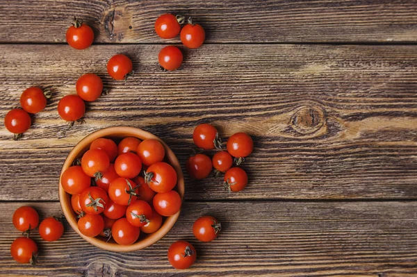 Top view of brown bowl with cherry tomatoes on dark wooden background, selective focus, copy space.