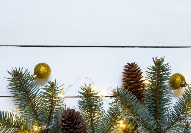 Beyaz ahşap arka planda Noel dalları, toplar ve koniler.