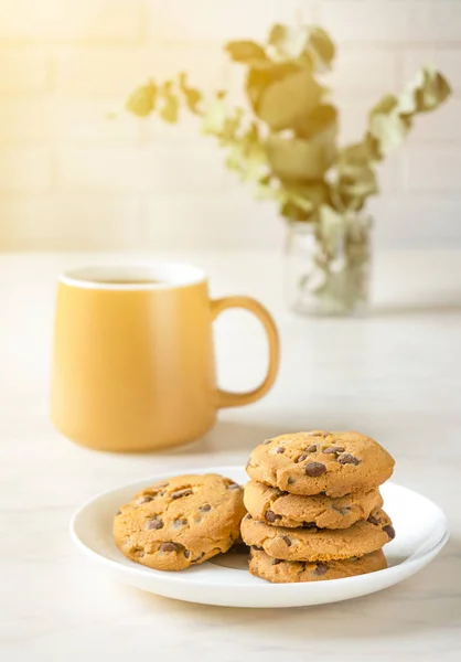 Biscuits au chocolat sur plaque blanche et thé sur table — Photo