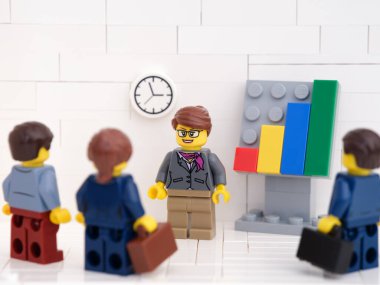 Tambov, Rusya Federasyonu - 16 Ekim 2021 Lego iş adamı minifigürler toplantı yapıyorlar ve başarılı takım çalışmalarının sonuçlarını gösteren grafikleri tartışıyorlar.