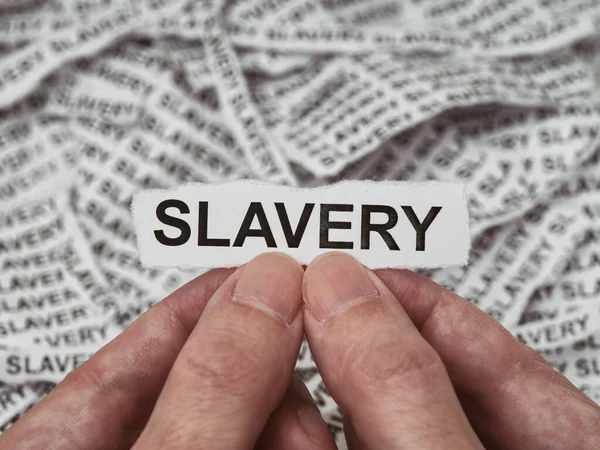 Man Holding Torn Piece Paper Word Slavery His Hands Pile — Stock Photo, Image