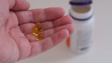  Elinde D vitamini kapsülleri tutan bir adam. Kapat..