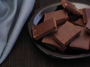 Siyah bir tabakta kırılmış siyah çikolata. Alçakgönüllülük. Kapat..