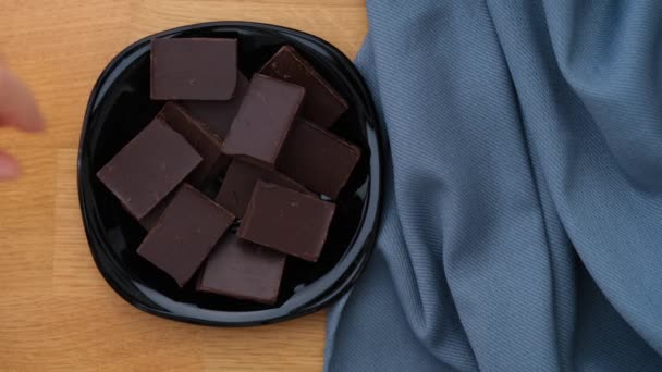 黒い皿からダークチョコレートの破片を拾う女性 閉じろ — ストック動画