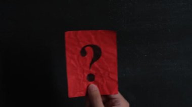 Üzerinde soru işareti olan kırmızı bir kağıt parçasını sallayan bir adam. Alçakgönüllülük. Kapat..