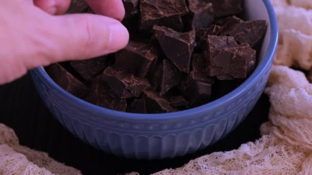 一个男人从蓝色的碗里拿出一块黑巧克力 靠近点 — 图库视频影像