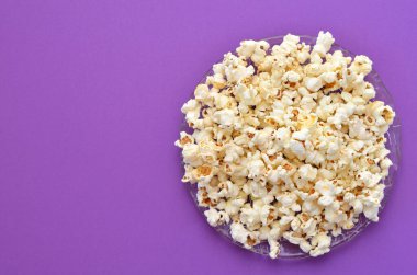 mor arkaplanda bir tabak patlamış mısır, kopyalama alanı