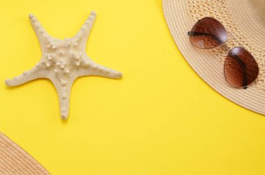 Yaz arkaplanı, denizyıldızı, sarı arka planda güneş gözlüğü şapkası.