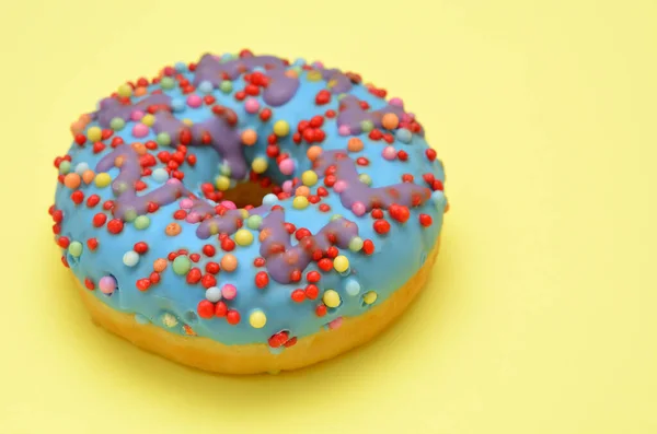 Bunter Donut Mit Blauem Sahnehäubchen Auf Gelbem Hintergrund Großaufnahme — Stockfoto