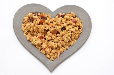 traditional organic muesli with dried fruits in a heart-shaped frame on a white background