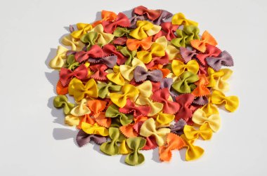 colorful farfalle pasta with natural extracts with hard shadows on white background