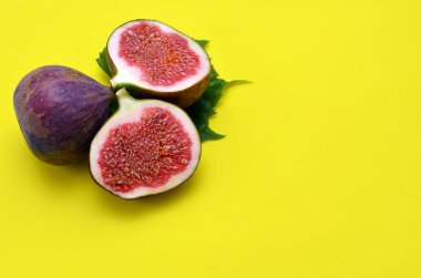 purple figs on yellow background close up, copy space