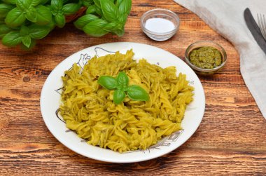 fusilli pasta with basil pesto sauce in a plate on a table close up