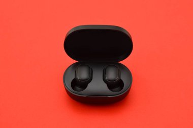 wireless headphones with box charger on red background, close up