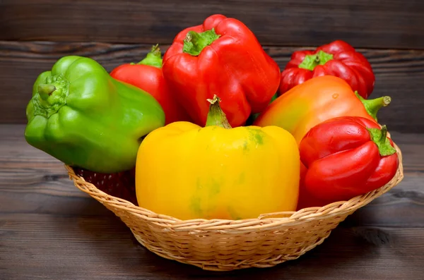 fresh red, green and yellow peppers on wooden basket