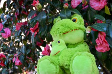 Çiçekli arka planda oyuncak kurbağalar