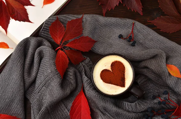 a cup of coffee with cream sprinkled with cocoa in the shape of a heart, autumn red image