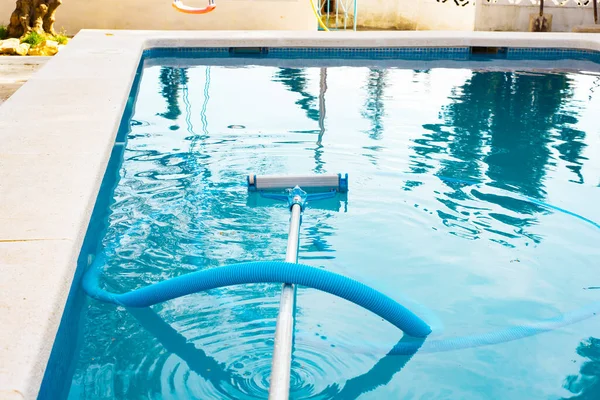 Una piscina sin personas con una manguera y una fregona una aspiradora para limpiar el agua de la piscina.preparación y limpieza de la piscina para la zona de baño —  Fotos de Stock