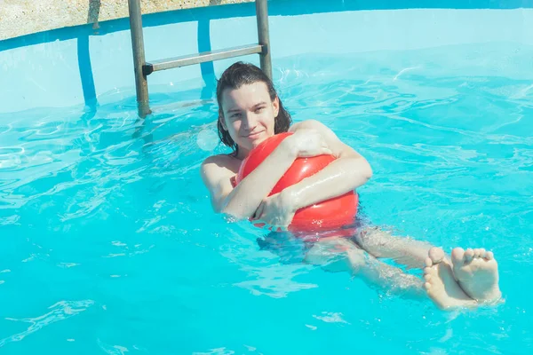 the boy sits on an inflatable swimming ring in the azure water of the pool, swimihg in the sun. boy child swims on an inflatable baby circle in the pool.