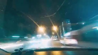 Gece şehirde dolaşırken. Yolda bir sürü araba var. Binaların ışıkları ve reklamlar. Bir arabanın kabininden zaman ayarlı