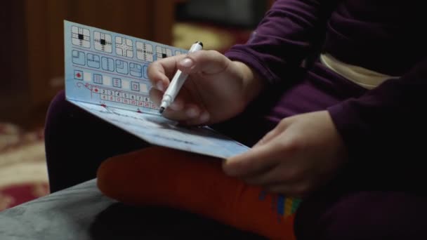 一个孩子在玩一个棋盘游戏 你必须在其中画一个平板电脑 他坐在沙发上 开发游戏的概念 2021年9月25日 俄罗斯克拉斯诺达尔 — 图库视频影像