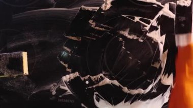 Yukarıdan bakıldığında, turuncu eldivenli bir kadının eli ev mutfağını cam sileceği ile temizliyor. Soba beyaz bir temizleyiciyle kaplanmış.