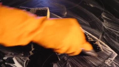 Üst manzara seramik elektrikli sobayı metal kazıyıcı ile temizliyor. Hob beyaz bir temizleyiciyle kaplıdır. Yakın plan.