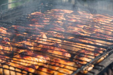 Kömür ızgarasında ızgarada kızarmış tavuk kanatlarının yakın çekimi. Kömürden duman yükselir. Seçici Odaklanma. Arka bahçe pişirme kavramı