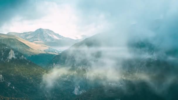 Nuages et brouillard recouvrent le sommet enneigé de la montagne et la gorge. Timelapse de montagne. — Video