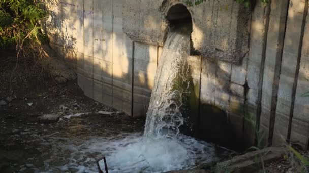 Des images au ralenti montrant l'écoulement des eaux usées tombant dans la rivière à partir d'un tuyau dans un mur de béton. Pollution de l'environnement. — Video