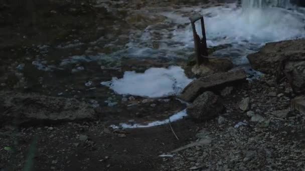 Close-up van het rioolwater dat uit een pijp in een betonnen wand in de rivier stroomt. Milieuvervuiling. Het begrip ecologie. — Stockvideo