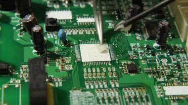 Makro video uygulaması cımbız ve işlemci koltuğunda bir tornavida kullanarak tahtaya akış yapıyor. Elektronik, bilgisayar, telefon ve televizyon tamirhanesi