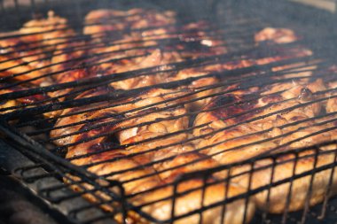Kömür ızgarasında ızgarada duran kızarmış tavuk kanatlarının yakın çekimi. Kömürden duman yükselir. Seçici Odaklanma. Arka bahçe pişirme kavramı