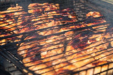 Kömür ızgarasının üzerinde duran altın kabuklu kızarmış tavuk kanadı. Kömürden duman yükselir. Seçici Odaklanma. Arka bahçe pişirme kavramı