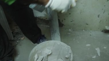 Bir tamirci kovadan alçı çıkarmak için mala kullanıyor. Trowel alçıyı duvara yapıştırıyor. Yakın plan. Odaları bitirme kavramı