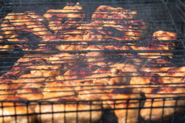 Altın kabuklu kızarmış tavuk kanatları ızgaranın üstünde siyah, yağlı bir ızgaranın üzerinde yatıyordu. Yakın plan. Seçici odaklanma. Arka bahçe pişirme kavramı