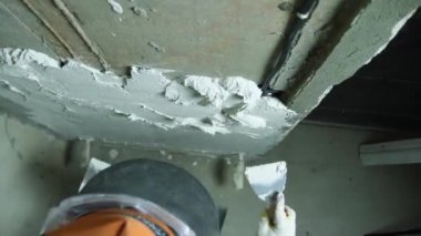 Bir tamirci duvarı iki malayla kaplıyor. Üst Manzara. Yakın plan. Odaları bitirme kavramı.