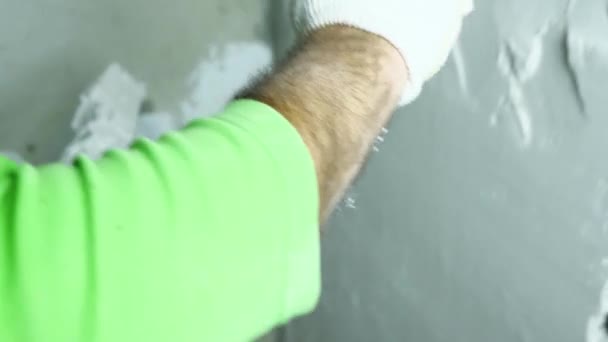 Финишер берёт штукатурку в ведро и разбрасывает её по стене лопаткой. Крупный план. Концепция отделки помещений. — стоковое видео