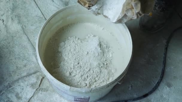 Top view of pouring plaster from a bag into a bucket of water. Close-up. The concept of repairing the premises. — Stock Video