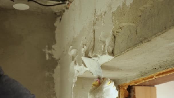 Primer plano del reparador alisando el yeso en la pared con una paleta. El concepto de acabado de la habitación. — Vídeo de stock