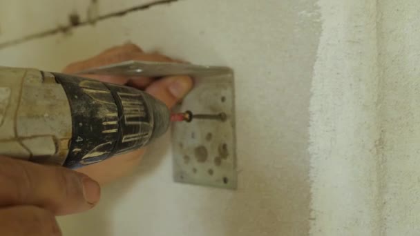 Close-up de fixação de um ângulo de metal com um parafuso auto-roscante para uma parede de concreto com uma chave de fenda elétrica. O conceito de decoração de interiores. — Vídeo de Stock