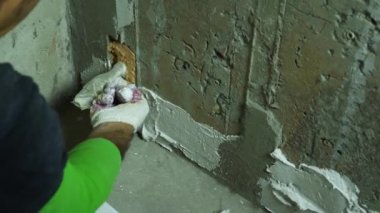 Bir adamın eldivenli elini beton duvara yapıştıran bir malayla yakından çek. Oda bitirme konsepti