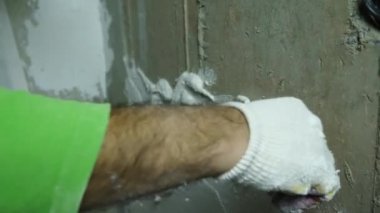 Bir dekoratör beton bir duvara alçı uyguluyor. Odaları bitirme kavramı