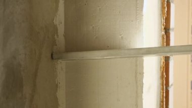 Yeni sıvanmış bir duvarın alüminyum bir kuralla yakınlaştırılması. Oda bitirme konsepti