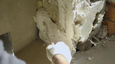 Bir inşaat işçisi kalın bir alçı tabakasını bir duvara uygular. Yakın plan. Odaları bitirme kavramı